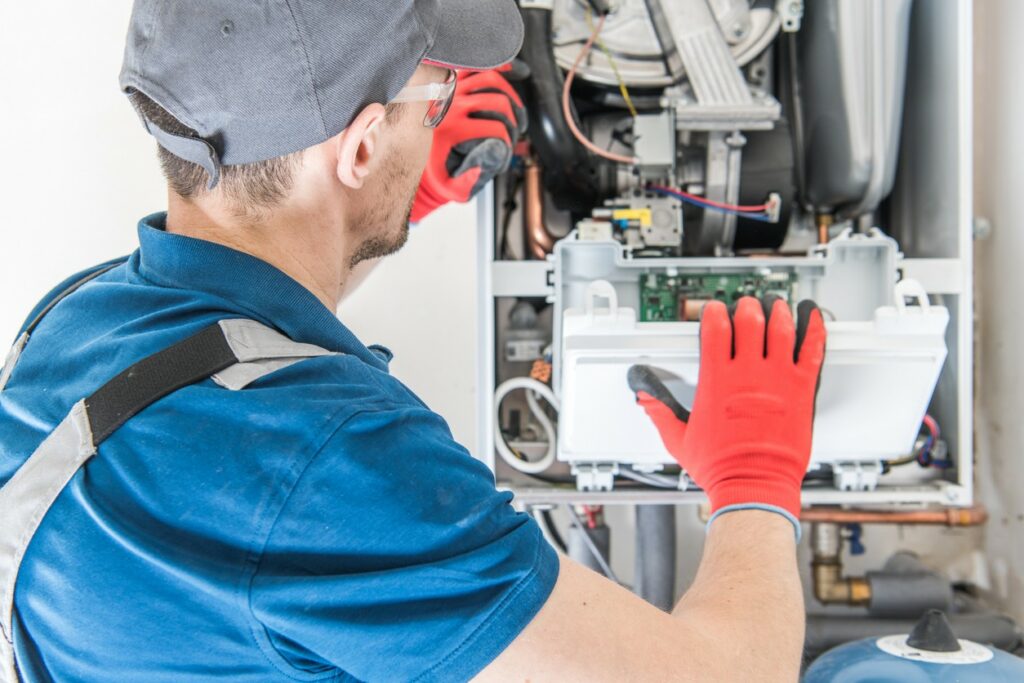An HVAC technician performs maintenance on a furnace.
