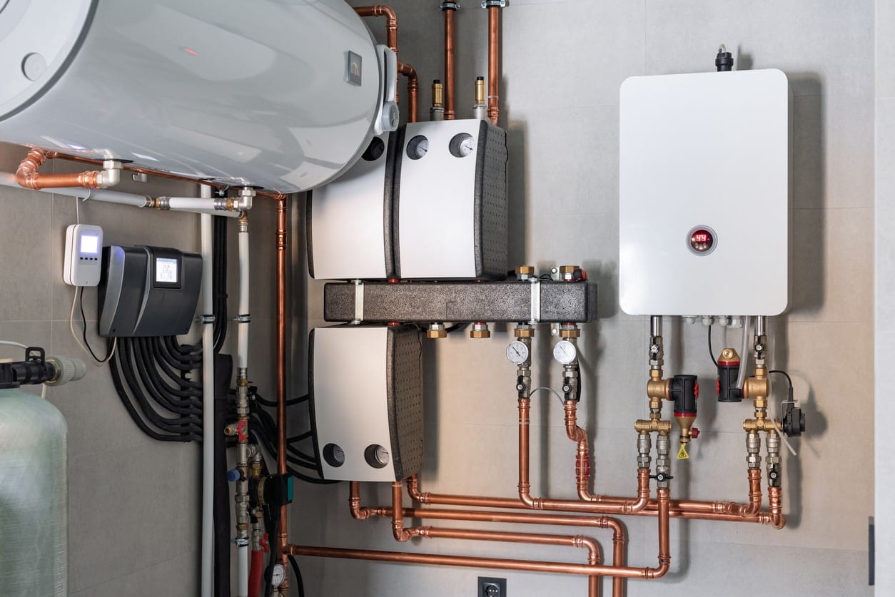 A collection of pipes, valves, and water heating equipment mounted on a wall, showcasing a modern plumbing setup.